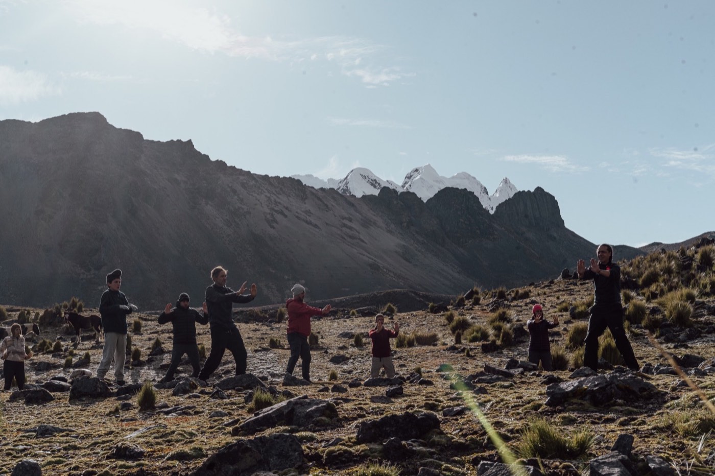 El grupo practica Chi Kung en las tierras altas frente a las montañas nevadas.