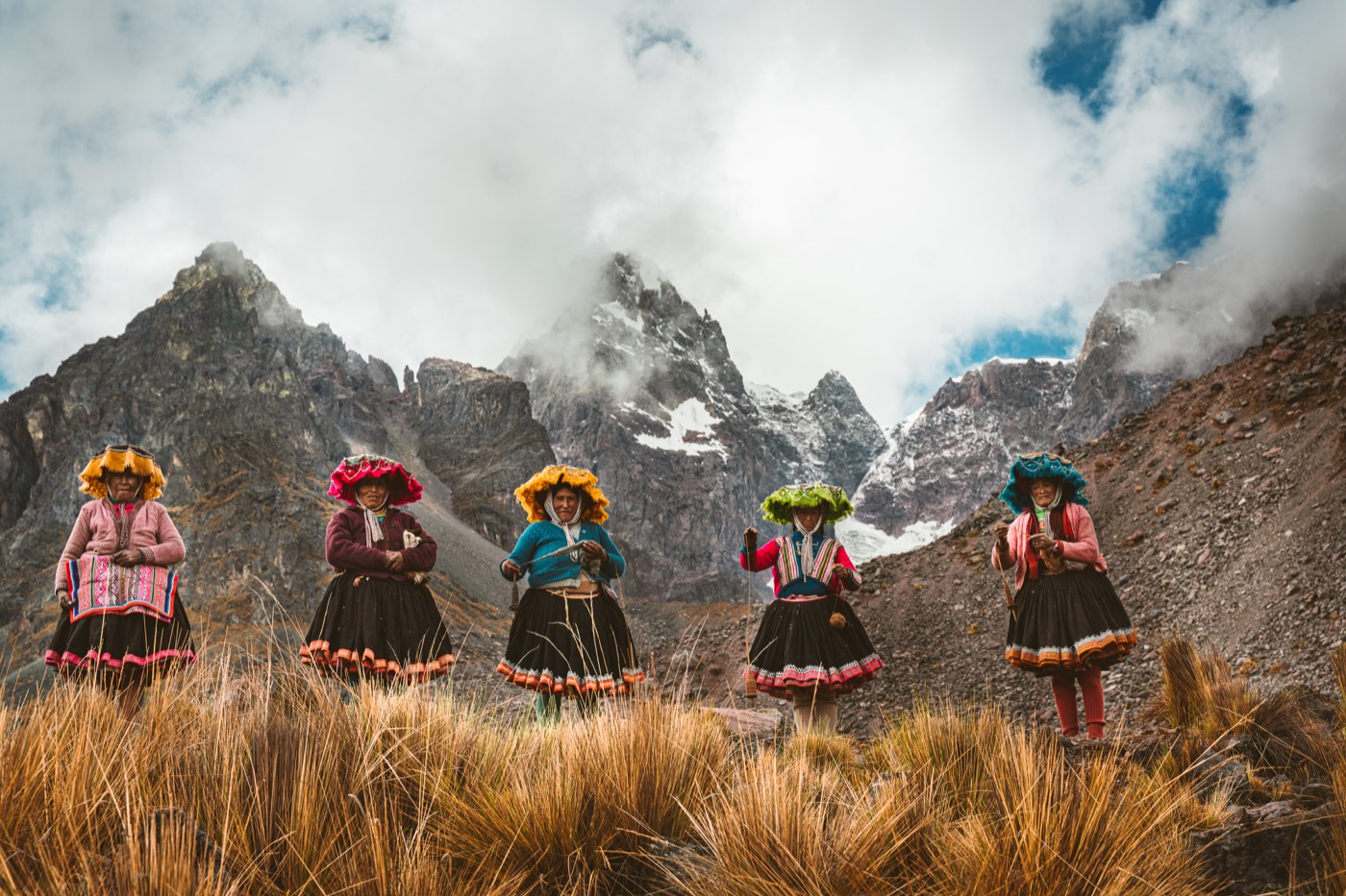Cinco mujeres Q’ero con vestimenta tradicional frente a las montañas.