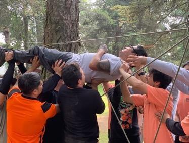 Un grupo trabaja en conjunto para superar un reto al aire libre.