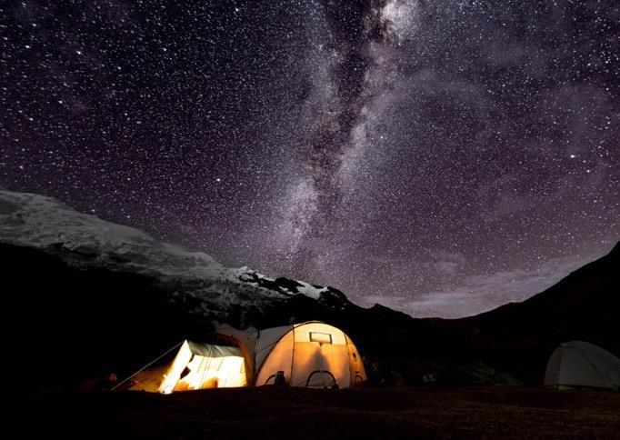 Tiendas de campaña iluminadas bajo un cielo estrellado.