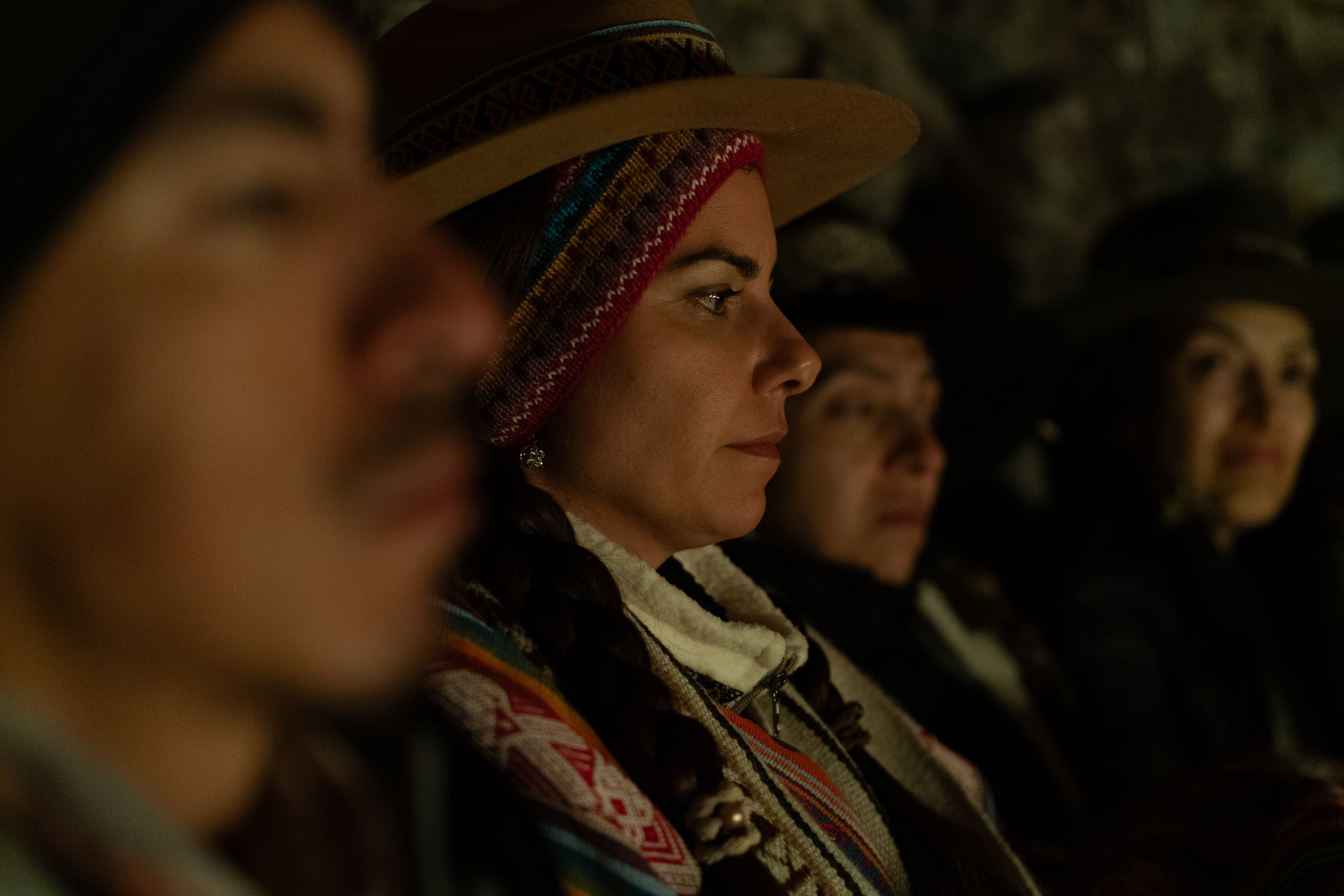 Participantes escuchan juntos en un espacio iluminado tenuemente